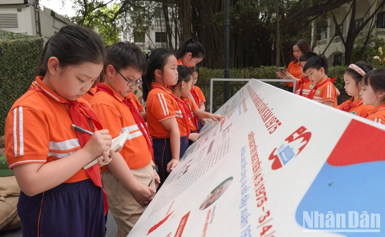 Les élèves notent les informations importantes de l’exposition pour rédiger leur compte rendu. Photo: nhandan.vn