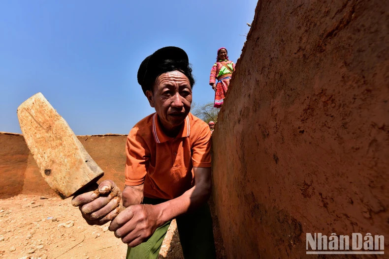 Vàng Si Hùng, avec minutie, tape la surface des murs, un savoir-faire transmis pour assurer solidité et beauté au fil du temps. Photo: nhandan.vn Vàng Si Hùng, avec minutie, tape la surface des murs, un savoir-faire transmis pour assurer solidité et beauté au fil du temps. Photo: nhandan.vn