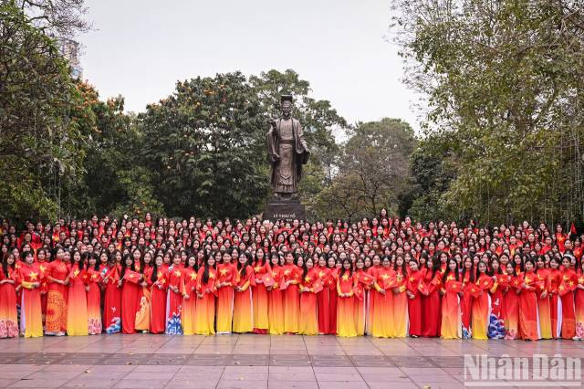 500 étudiantes de l’Académie des femmes du Vietnam, habillées d’ao dài rouges ornés d’une étoile jaune, posent pour une photo souvenir devant la statue du roi Ly Thai Tô. Photo : nhandan.vn