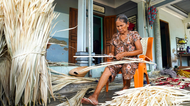 Une artisan est en train de tresser un éventail en feuilles de « buông ». Photo : daidoanket.vn Une artisan est en train de tresser un éventail en feuilles de « buông ». Photo : daidoanket.vn