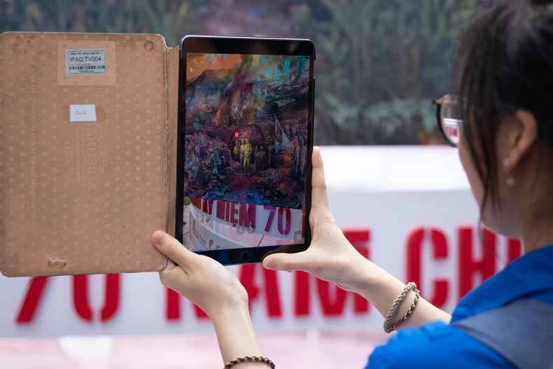 En scannant le code QR sur la peinture, les étudiants peuvent rechercher des informations sur les 56 jours et nuits de combats de la campagne de Diên Biên Phu. Photo : nhandan.vn En scannant le code QR sur la peinture, les étudiants peuvent rechercher des informations sur les 56 jours et nuits de combats de la campagne de Diên Biên Phu. Photo : nhandan.vn