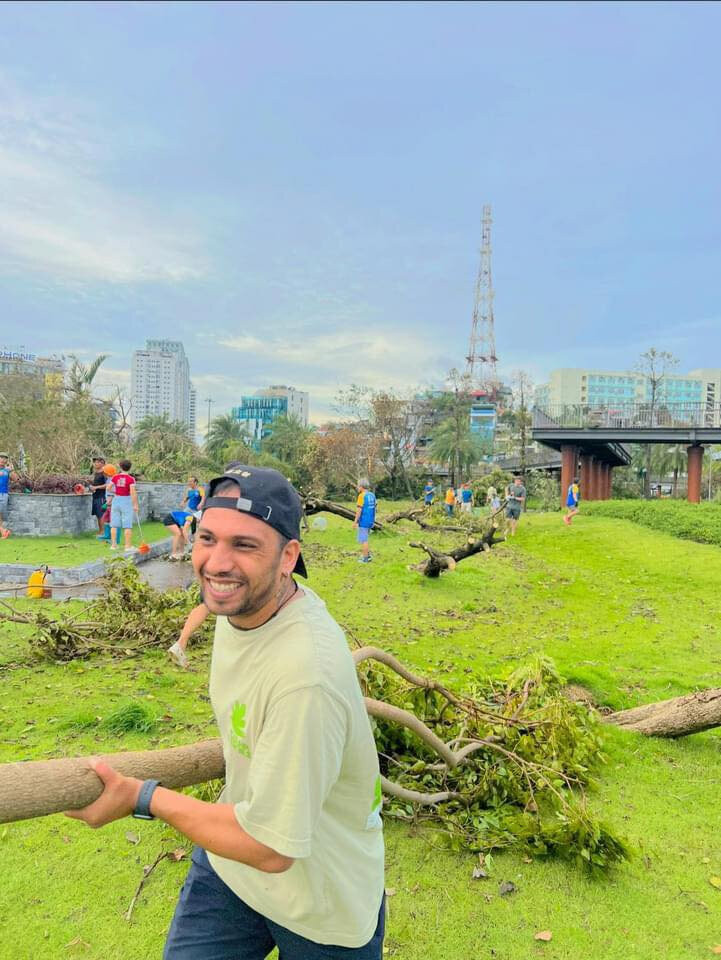 Un jeune homme étranger affiche un large sourire en aidant les habitants à dégager les arbres tombés. Photo : vtcnews.vn Un jeune homme étranger affiche un large sourire en aidant les habitants à dégager les arbres tombés. Photo : vtcnews.vn
