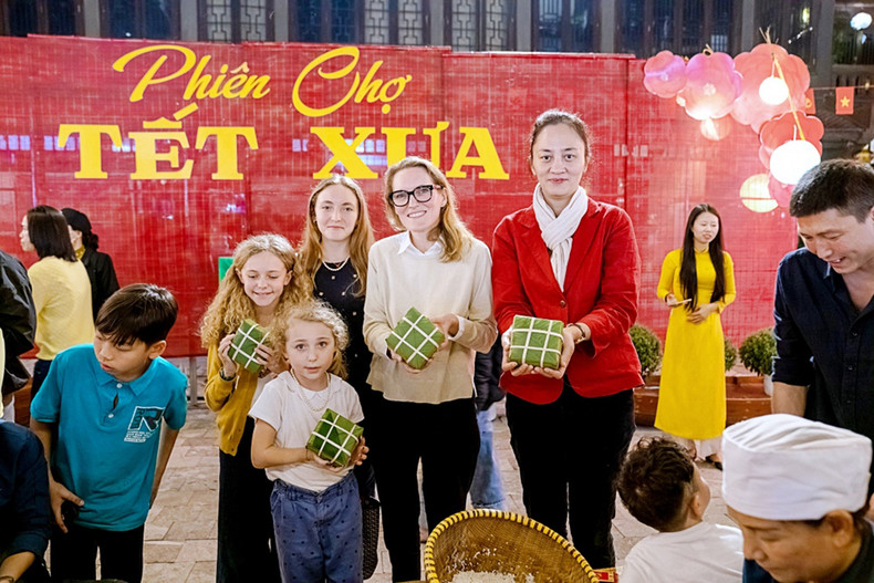 Les visiteurs internationaux font l'expérience de l'emballage du "bánh chưng" lors e la reconstitution du Têt d’antan et le marché traditionnel de l’ancienne capitale de Hoa Lu. Photo : Service du Tourisme de Ninh Binh.