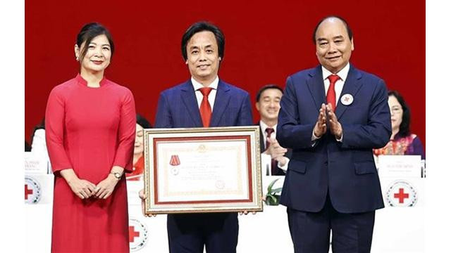 Le Président Nguyên Xuân Phuc (à droite) remet l'Ordre du Travail de 3e classe au Centre de télévision humanitaire relevant du Comité central de la Croix-Rouge du Vietnam. Photo: VNA