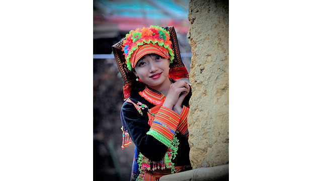 En costumes traditionnels sophistiqués à côté de la maison traditionnelle aux murs en torchis « nhà trình tường », il s’agit d’un portrait d’une fille de l’ethnie Dao rouge dans les hautes terres de Lai Châu. Photo : baodantoc.vn