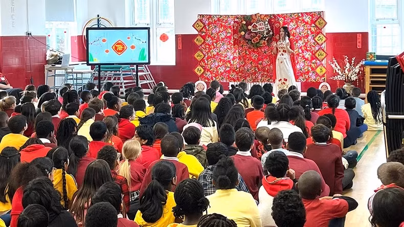 Les élèves de l’Ark Oval Primary Academy ont écouté la créatrice d'origine vietnamienne Anna Hoang présenter sa collection d'áo dài (tenue traditionnelle vietnamienne). Photo: LOANI VN-UK