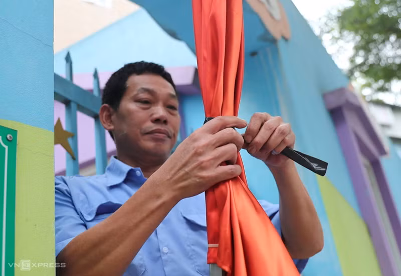 Un agent de sécurité d'une école maternelle de la rue Hai Ba Trung a utilisé un ruban noir pour attacher une partie du drapeau national avant de l'accrocher à la porte.