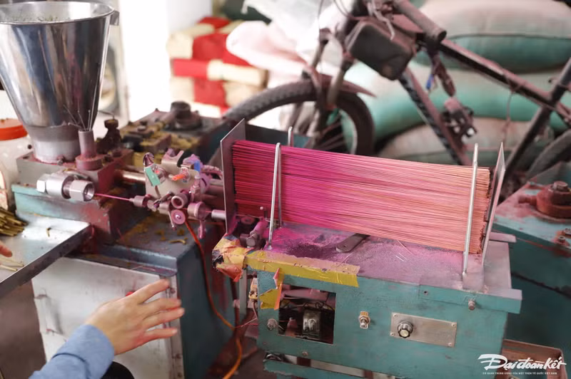 Après avoir séché, les tiges de bambou sont insérées dans une machine pour être taillées, avant d’être plongées dans du colorant rose. Le bâton est ensuite enrobé d’une pâte aromatique, puis est séché à nouveau. Photo: daidoanket.vn.
