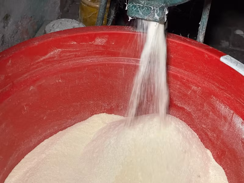 Le riz doit être bien lavé, égoutté et mélangé à de la poudre de curcuma pour lui donner une jolie couleur. Il est soigneusement moulu jusqu’à obtenir une consistance fine.
