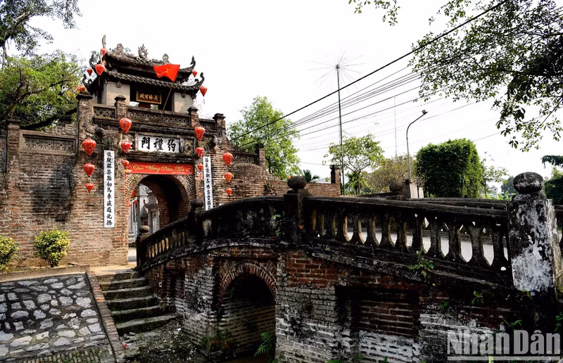 C’est par un pont arqué de deux mètres de large et de dix mètres de long que l’on entre dans le village. Précédemment, le fossé situé en dessous du pont est une tranchée profonde entourant tout le village, où étaient plantés des arbres de bambous. Cette tranchée servait de mur de protection contre les voleurs. Photo : The Duong /NDEL