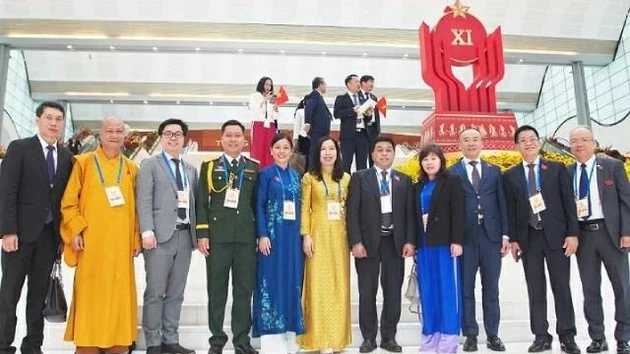 La vice-ministre des Affaires étrangères Lê Thị Thu Hằng pose pour une photo avec une délégation de Vietnamiens à l'étranger exemplaires venus assister au XIᵉ Congrès national d’émulation patriotique, le 27 décembre 2025. Photo : baoquocte.vn