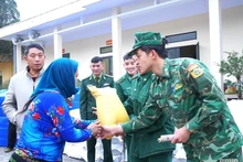 Sourire aux lèvres, les soldats remettent avec attention les cadeaux du Têt aux habitants. Photo : QĐND. 