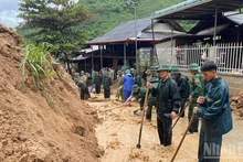 Les soldats de la Garde-frontière de la région montagneuse de Thanh Hoa dégagent la terre et les rochers tombés de la pente sur la route locale. (Photo : NDEL)