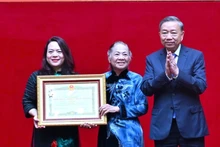 Le secrétaire général du Parti Tô Lâm (droite) remet la distinction à la famille du général Bui Thien Ngo. Photo: TPO.