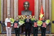 Le président Luong Cuong remet les décisions de promotion au grade de général de corps d’armée à quatre officiers supérieurs de l’Armée et de la Police populaires du Vietnam. Photo : NDEL.