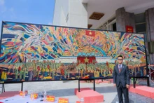 Le peintre Chu Nhat Quang à côté de la peinture sur laque grand format, sans assemblage, « l’Oncle Hô lit la Déclaration d'indépendance ». Photo : NDEL.