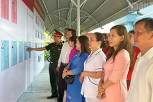 Des cadres et des habitants consultent les listes des candidats.