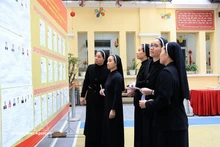 Des religieuses de la Congrégation des Amantes de la Sainte-Croix, au 31 rue Nhà Chung, consultent la liste des candidats au bureau de vote n°1, dans le quartier de Hoàn Kiem. Photo : VNA