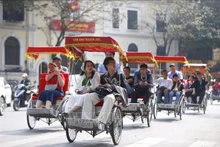 Des touristes font le tour du lac Hoan Kiem en cyclo-pousse. Photo : VNA.