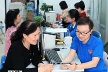 Des jeunes volontaires de Hàng Bồ (Hanoï) aident les habitants dans les démarches administratives en ligne. Photo : VNA.