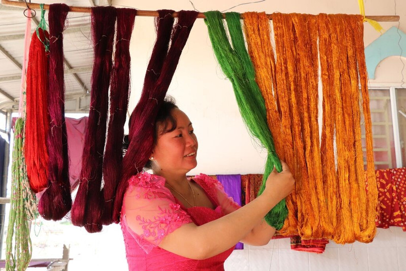 Chanh Da Ty, patronne d’un atelier de tissage dans la commune de Van Giao, vérifie la soie après sa teinture. 