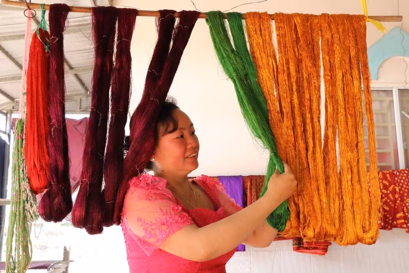 Chanh Da Ty, patronne d’un atelier de tissage dans la commune de Van Giao, vérifie la soie après sa teinture. 