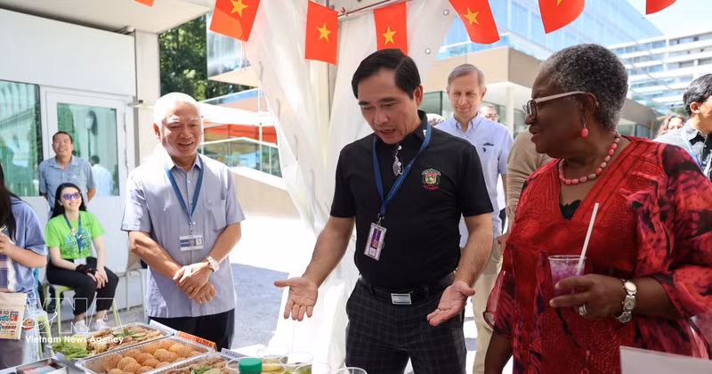 Le conseiller Pham Quang Huy (en chemise noire) présente le stand vietnamien à la directrice générale de l'OMC, Ngozi Okonjo-Iweala. Photo : VNA. 