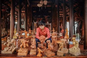 Tran Duy aux côtés de ses sculptures sur bois, mêlant savoir-faire artisanal traditionnel et inspiration contemporaine, dans l’atelier familial à Quang Nam. (Photo fournie par le personnage)