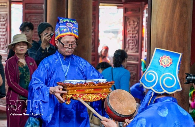 Les quatre marmites de riz sont introduites dans la maison communale pour être présentées en offrande au génie tutélaire du village. Photo : VNA.