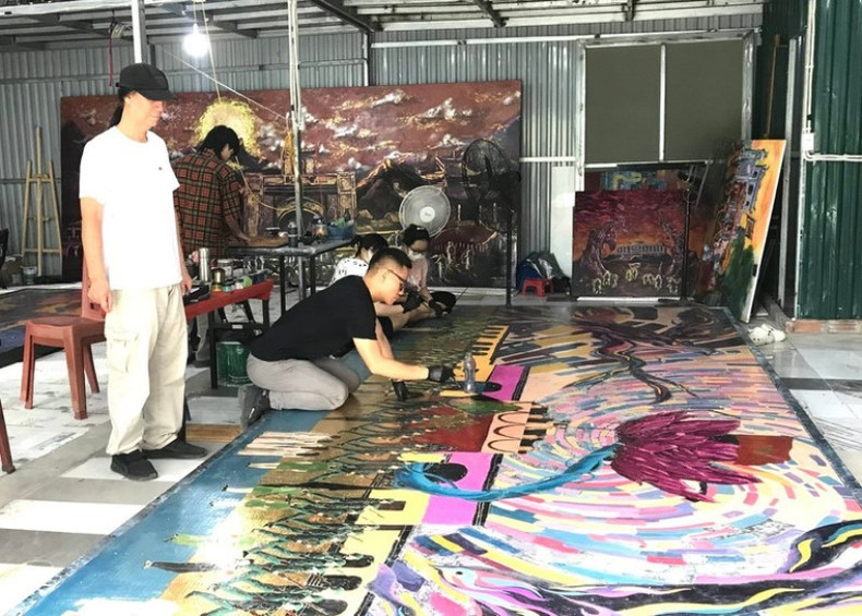 Le peintre Chu Nhat Quang, guidé par son père, l’artiste émérite Chu Luong, met la dernière touche à l’œuvre. Photo : NDEL. laque-chu-luong.jpg