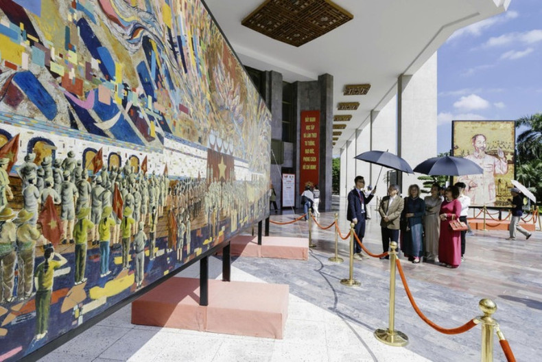 Le peintre Chu Nhat Quang présente l'œuvre « l’Oncle Hô lit la Déclaration d'indépendance ». Photo : NDEL. laque-presente.jpg