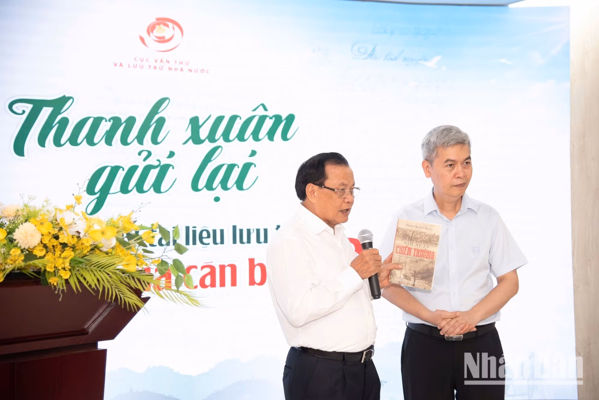 Pham Quang Nghi, ancien membre du Bureau politique, ancien secrétaire du Comité municipal du Parti de Hanoï et ancien cadre envoyé au front Sud (à gauche), remet à Dang Thanh Tung un exemplaire de son ouvrage intitulé « Là-bas, c’était le champ de bataille » (Nơi ấy là chiến trường). Photo : NDEL