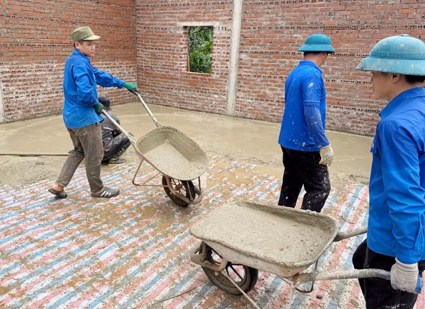 Les jeunes volontaires apportent leur aide à la construction de maisons et au coulage de dalles en béton pour les familles bénéficiaires des politiques sociales. Photo : TPO