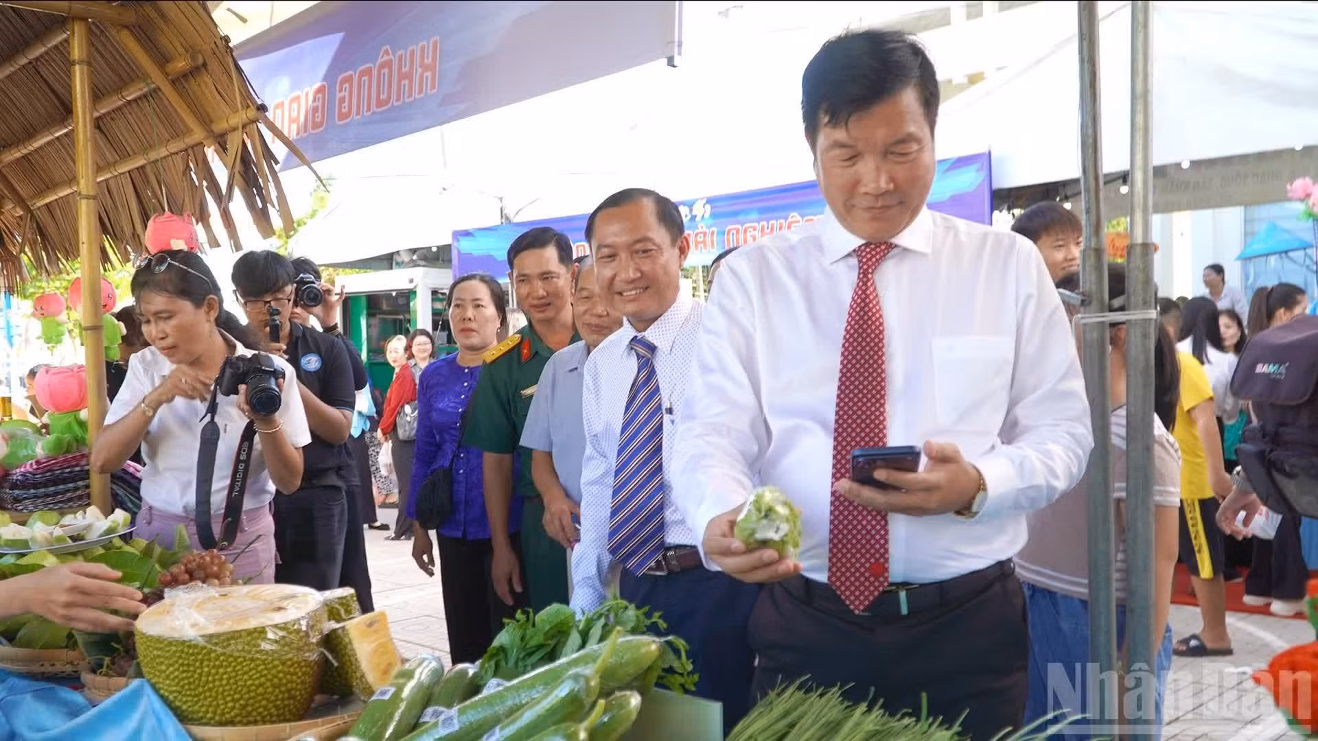 Vo Phan Thanh Minh, secrétaire du Comité du Parti du quartier de My Ngai, accompagné de délégués et d'habitants, en visite des stands des produits agricoles dotés de codes QR pour la traçabilité. Photo : NDEL.