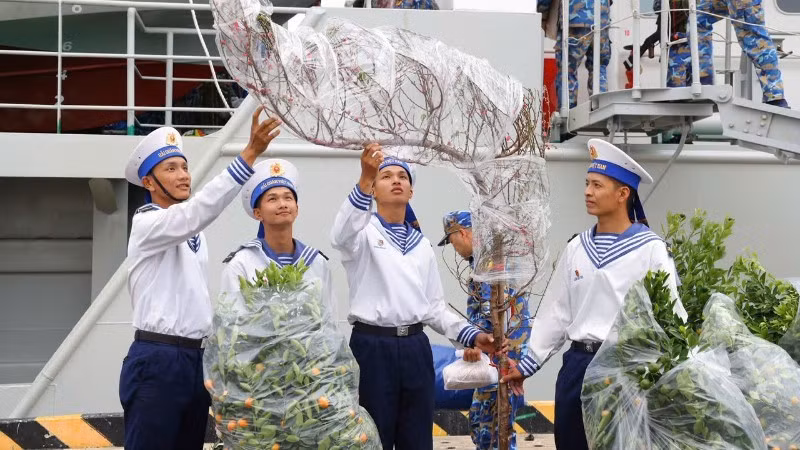 De jeunes soldats auprès des pêchers et des kumquatiers du printemps, accueillant le Têt 2026. Photo : NDEL.