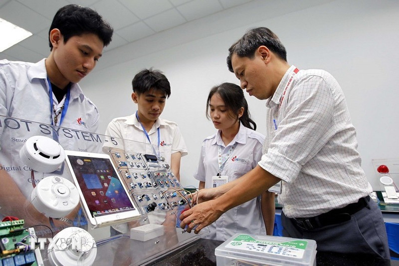 Des professeurs de la faculté de technologie électronique de l'université industrielle de Hô Chi Minh-Ville encadrent les étudiants dans leurs études et leurs recherches au laboratoire IoT et IA. Photo : VNA.