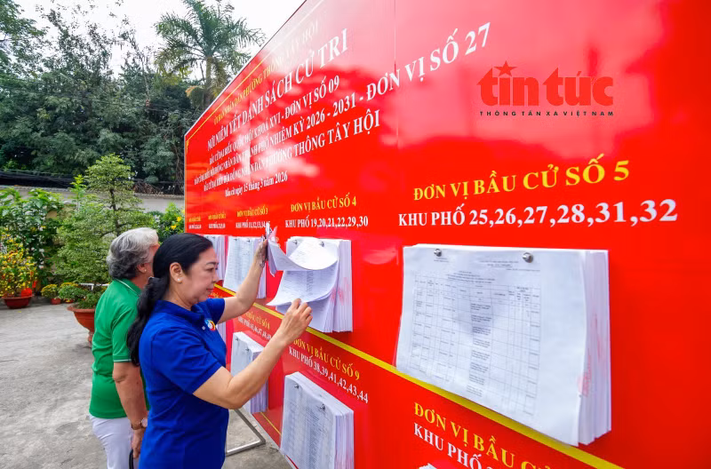 Des habitants consultent les informations électorales dans l’espace réservé à l’affichage de la liste des électeurs au Comité populaire du quartier de Thong Tay Hoi.