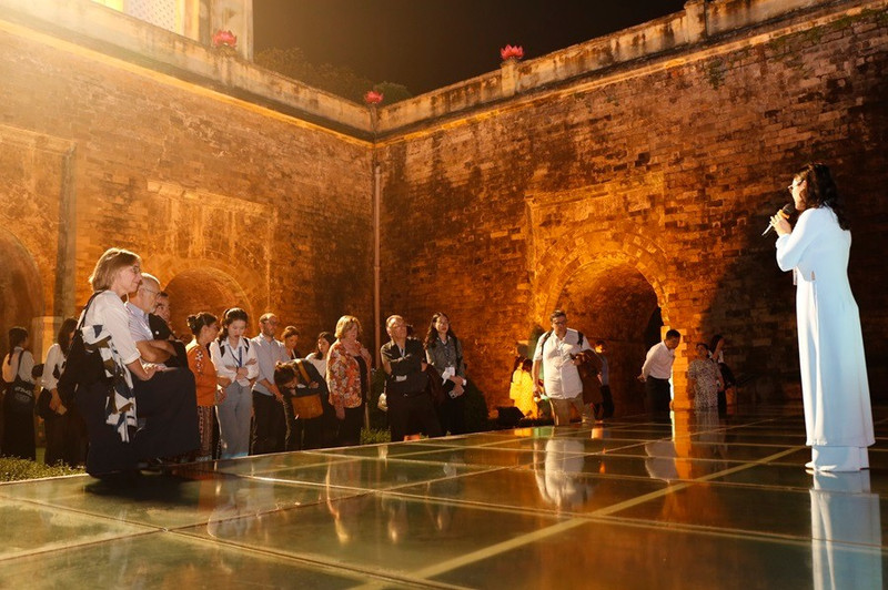 Des visiteurs étrangers vivent une expérience unique en découvrant la Citadelle impériale de Thang Long lors d’une visite nocturne. Photo : Hanoimoi.
