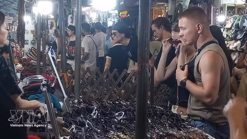 Des visiteurs étrangers aiment flâner et acheter des souvenirs au marché nocturne du Vieux Quartier de Hanoï. Photo : VNA.