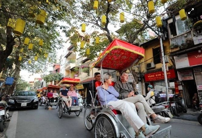 Les touristes étrangers visitent les rues en cyclo-pousse, admirant la beauté antique d'Hanoï. Photo : VNA.