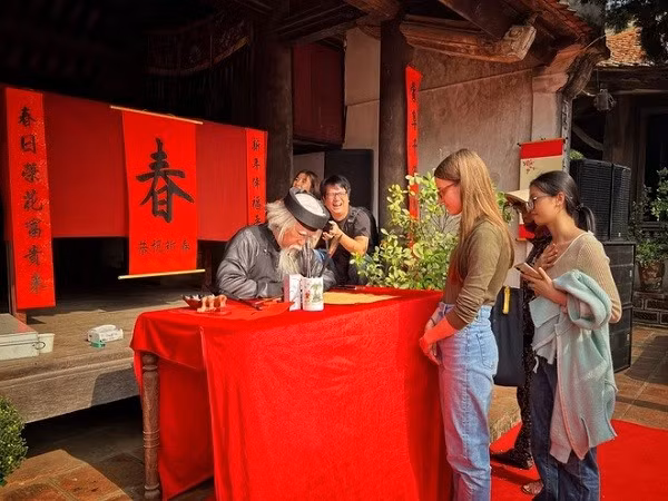Un vieux calligraphe en plein travail, sous le regard admiratif des visites étranger. Photo : VNA. Un vieux calligraphe en plein travail, sous le regard admiratif des visites étranger. Photo : VNA.