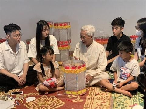 L’artisan Nguyên Van Quyên (centre) présente la fabrication d’une lanterne "keo quân" au Musée d’ethnographie du Vietnam, à Hanoi. Photo : VNA. 