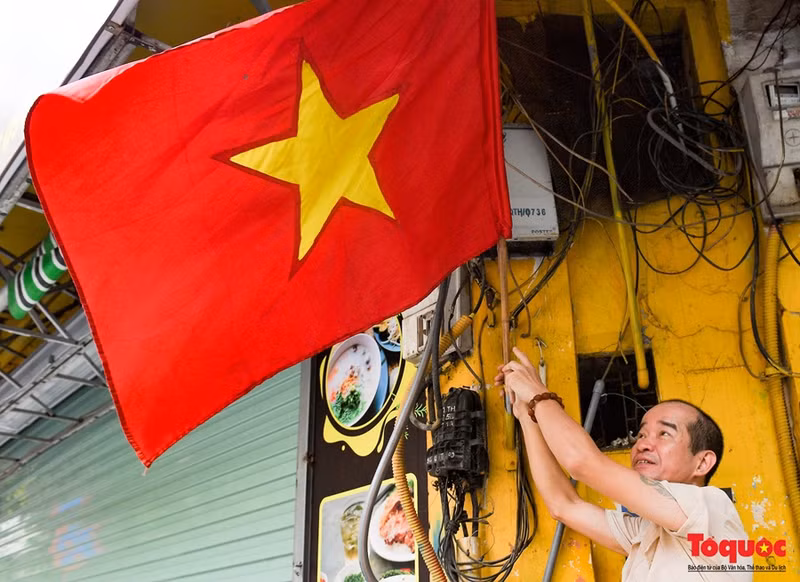 Un homme accroche le drapeau national pour célébrer les grandes fêtes du pays.