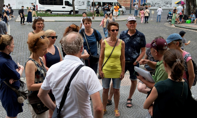 Touristes étrangers écoutant un guide devant la Poste centrale de Saïgon, le 18 juin 2023. Photo: VnExpress 