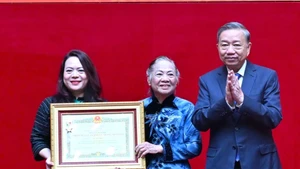 Le secrétaire général du Parti Tô Lâm (droite) remet la distinction à la famille du général Bui Thien Ngo. Photo: TPO.