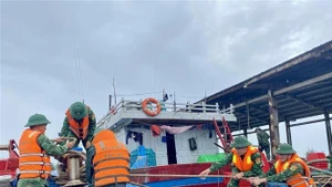 Des gardes-frontières aident des pêcheurs à consolider et à amarrer leurs bateaux. Photo : VNA.
