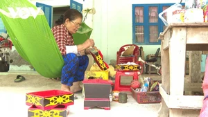 Madame Trieu Thi Vui est en train de peindre les motifs sur le plateau à bétel et noix d’arec