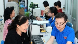 Des jeunes volontaires de Hàng Bồ (Hanoï) aident les habitants dans les démarches administratives en ligne. Photo : VNA.