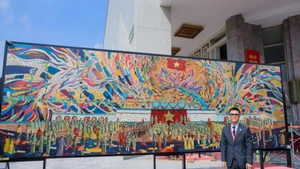 Le peintre Chu Nhat Quang à côté de la peinture sur laque grand format, sans assemblage, « l’Oncle Hô lit la Déclaration d'indépendance ». Photo : NDEL.