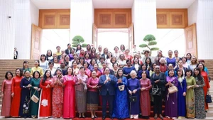 Le Premier ministre vietnamien Pham Minh Chinh et son épouse (en "ao dai" bleu) rencontrent à Hanoi des femmes diplomates vietnamiennes et étrangères en poste au Vietnam. Photo : VNA.